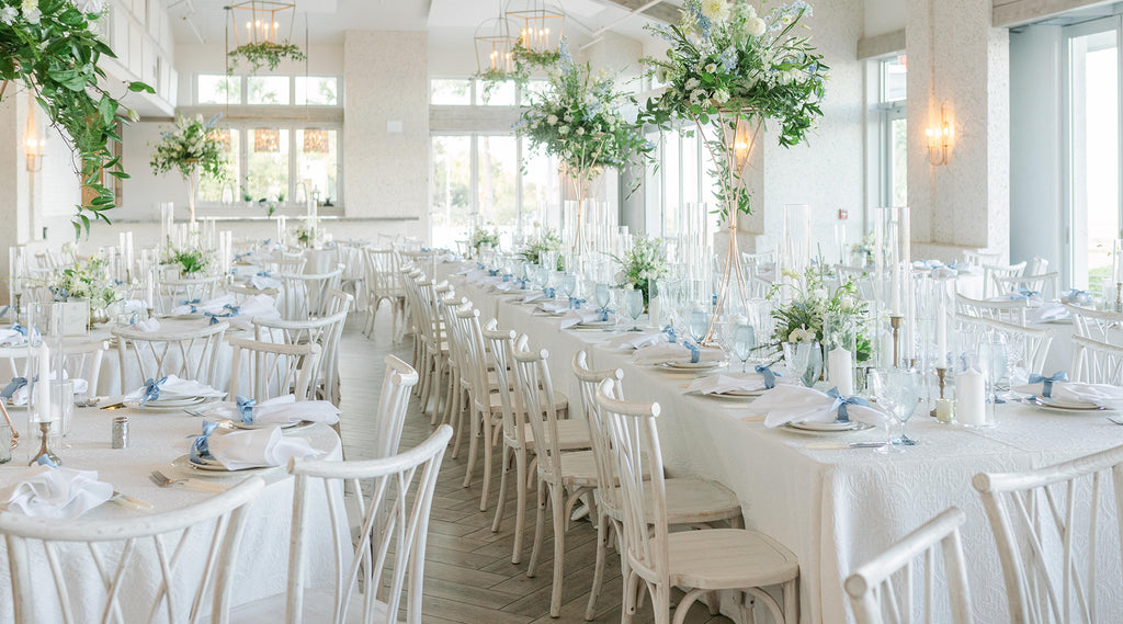 Dining chairs arranged at long tables, with flowers and place settings.
